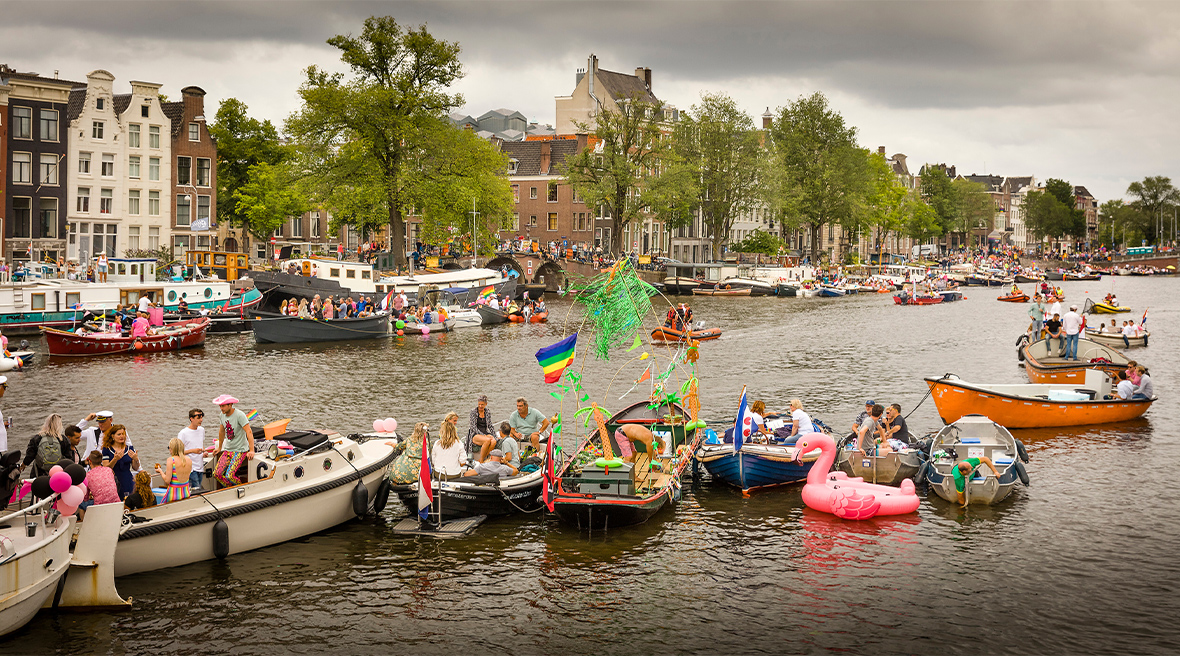 Boats with Pride revellers in a canal in Amsterdam